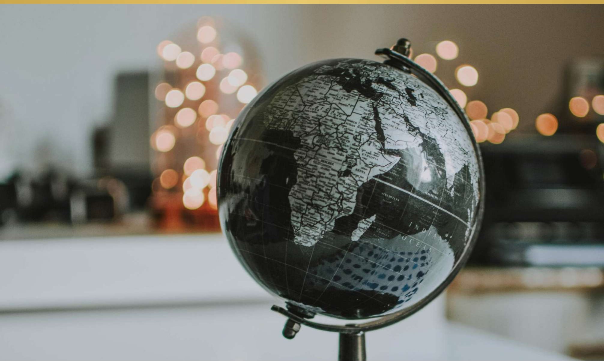 A dark globe on a desk, backlit by warm bokeh lights.